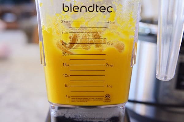 A blendtec blender with pureed pumpkin.