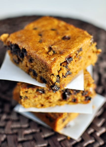 A stack of pumpkin chocolate chip blondies on pieces of parchment paper.