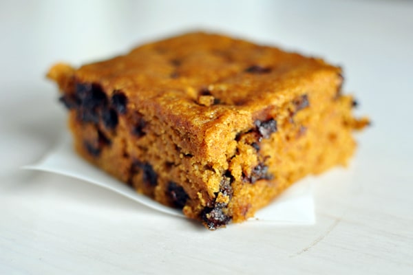 Square of pumpkin chocolate chip blondie on a piece of parchment paper.