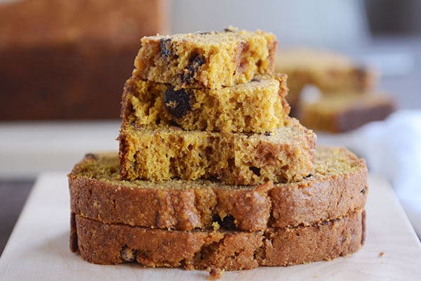 Thick slices and pieces of pumpkin chocolate chip bread stacked on top of each other. 