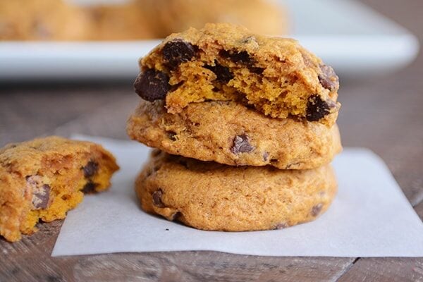 A stack of cakey pumpkin chocolate chip cookies with the top cookie split in half.