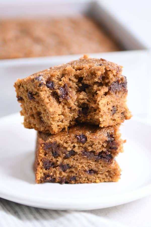 Two pieces of pumpkin chocolate chip snack cake stacked with bite taken out.