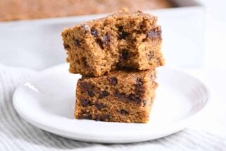 Two pieces of pumpkin chocolate chip snack cake stacked with bite taken out.