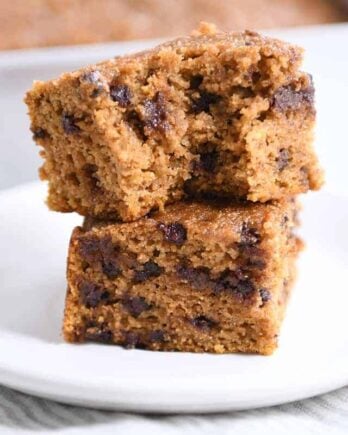 Two pieces of pumpkin chocolate chip snack cake stacked with bite taken out.