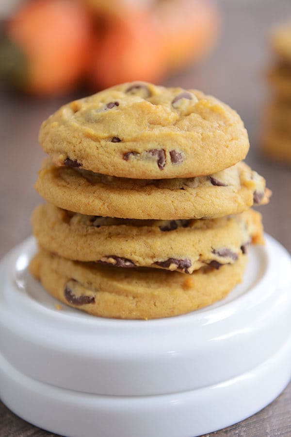 A stack of chocolate pumpkin cookies on top of a turned over white ramekin.