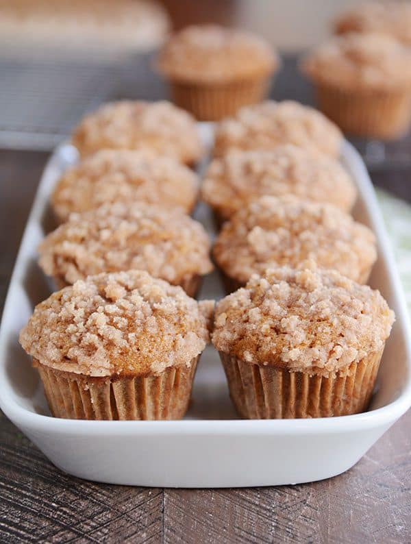 A white dish full of streusel-topped pumpkin muffins.