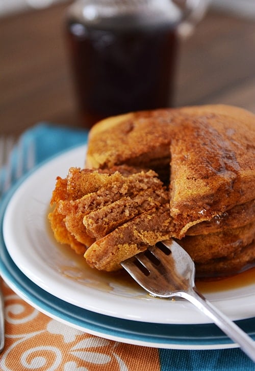 A big stack of pumpkin pancakes with a bite getting taken out of all of them.