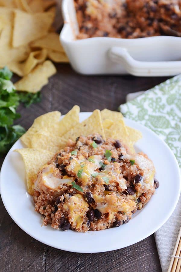 A white plate with cheesy black bean quinoa bake next to a helping of tortilla chips.