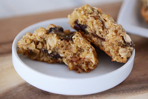 An oat chocolate chip cookie split in half on a small white plate.