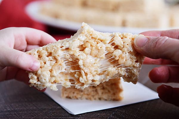 A rice krispie treat being pulled apart with two hands.