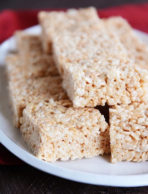 A white plate full of cut up square rice krispie treats. 