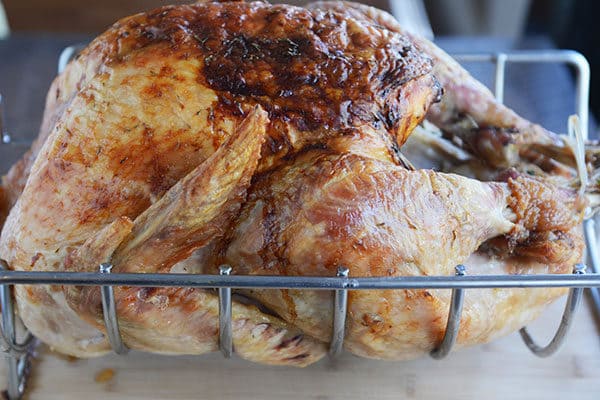 A golden brown roasted turkey in a roasting rack. 