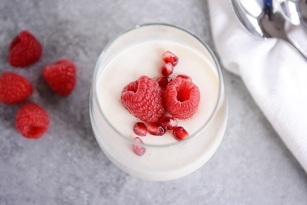 Top view of a glass cup full of cream topped with berries.