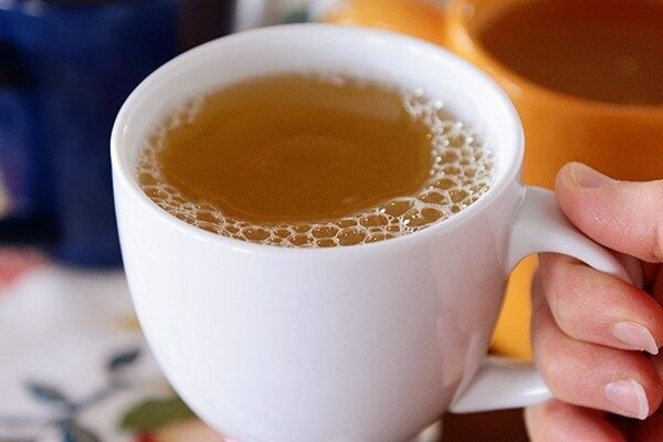 Hand holding a white mug of tea. 