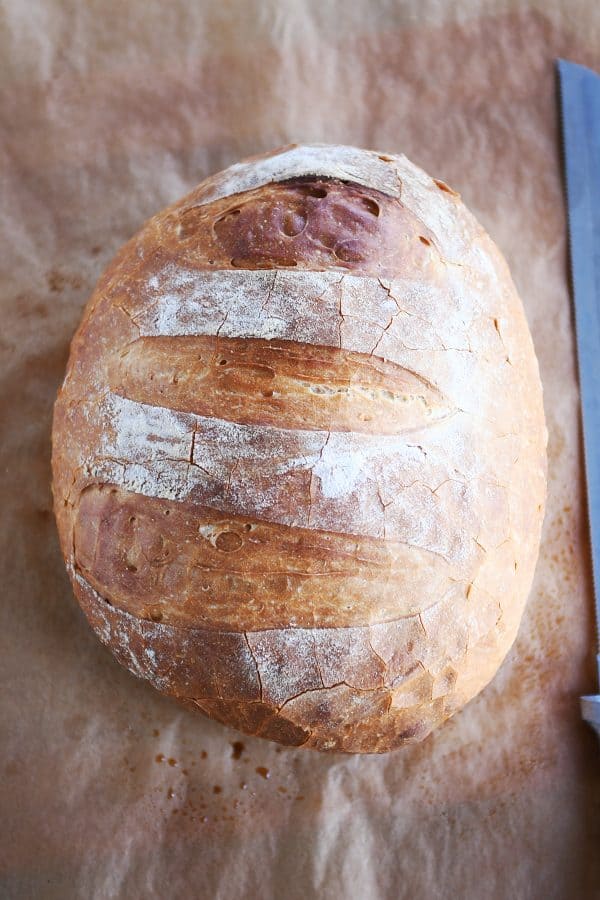 Loaf of rustic crusty bread on parchment paper.