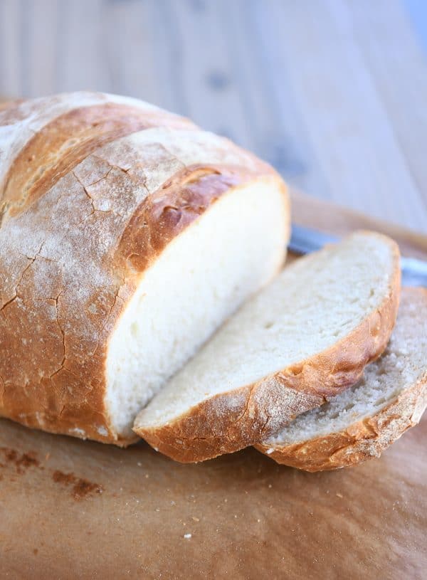 Loaf of rustic crusty bread with two slices cut.