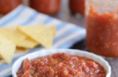 Ramekin of homemade salsa, in front of a half empty jar of salsa and tortilla chips.