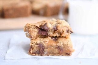 Two salted caramel brown butter chocolate chip bars stacked on each other on white wax paper.