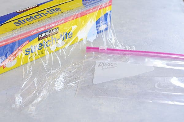 Saran wrap and a Ziploc bag on a white countertop.