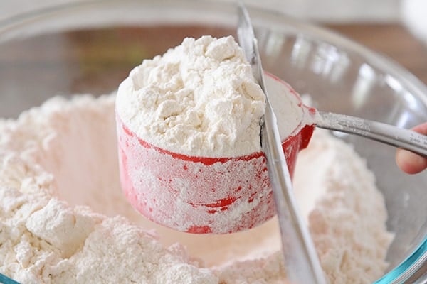 A butter knife leveling off a cup of flour. 