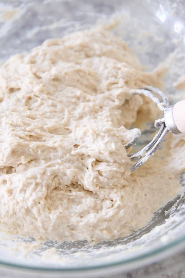 Mixing dough for easy focaccia bread in glass bowl. 