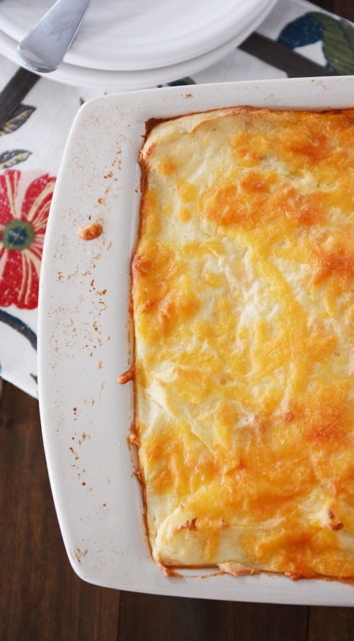 Top view of golden brown baked cheesy potatoes in a white dish.