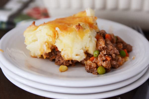A serving of shepherd's pie on a stack of white plates.
