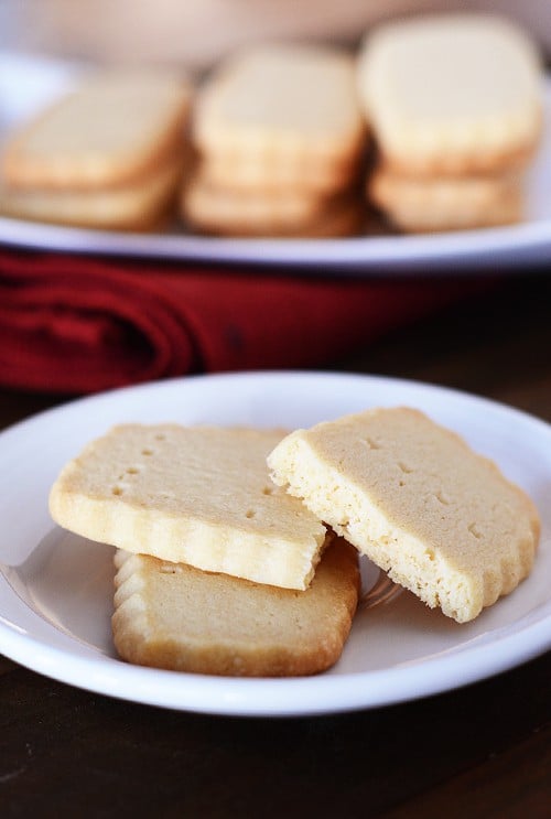 Two Scottish shortbread cookies with one split in half on a white plate.