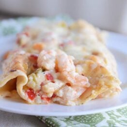 Closeup of two shrimp enchiladas on white plate.