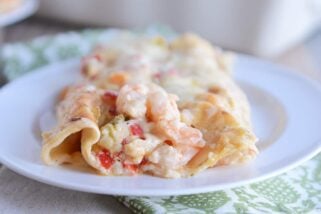 Closeup of two shrimp enchiladas on white plate.