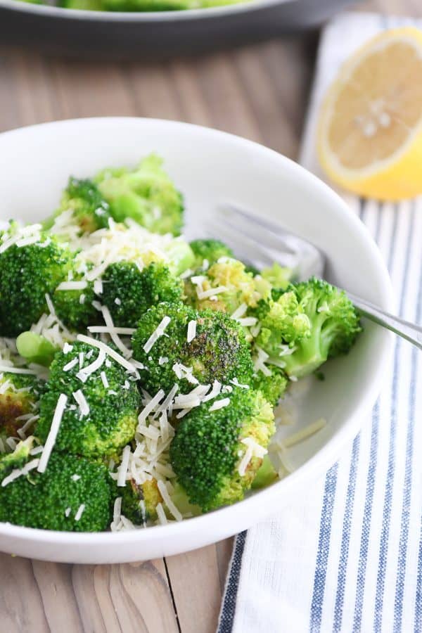 White bowl with skillet broccoli and Parmesan.