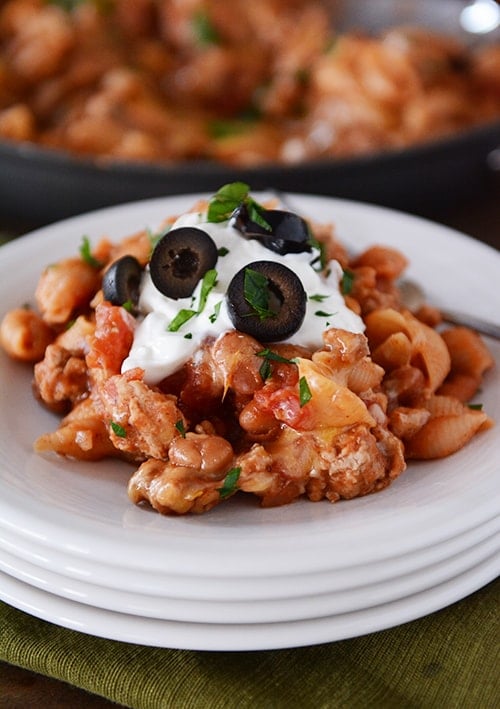 A stack of white plates with a helping of taco pasta shells.