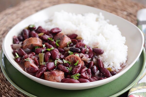 Red beans and sausage next to cooked white rice in a large bowl.