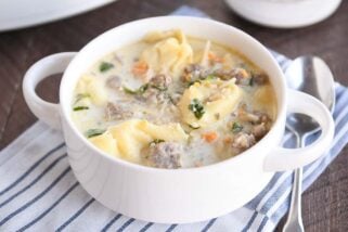 White bowl with slow cooker tortellini sausage spinach soup.