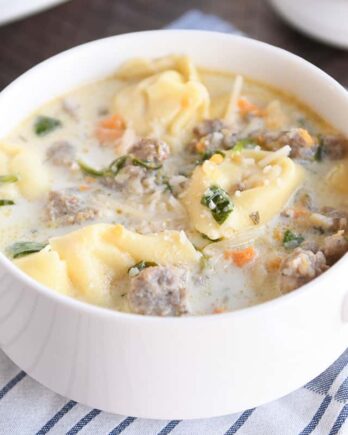 White bowl with slow cooker tortellini sausage spinach soup.