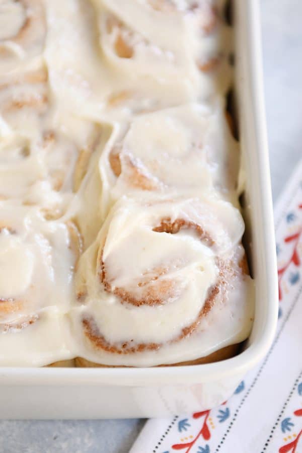 Small batch cinnamon roll recipe with dough baked and frosted in white pan.