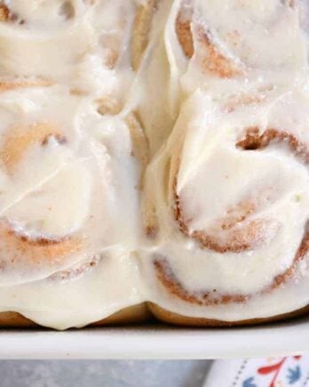 Small batch cinnamon roll recipe with dough baked and frosted in white pan.