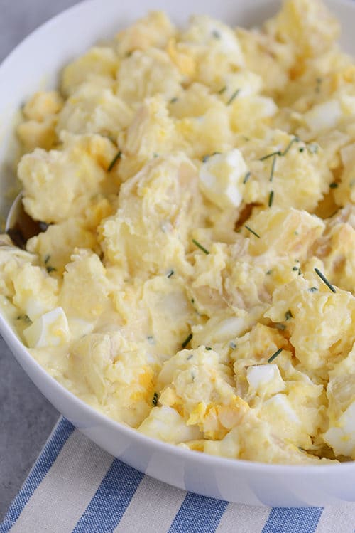 A white bowl full of creamy yukon gold potato salad.