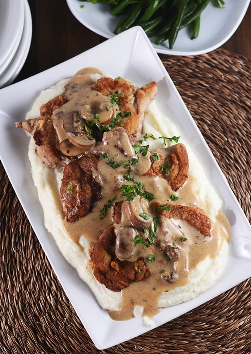 Crispy pork cutlets over mashed potatoes and topped with a brown mushroom sauce. 