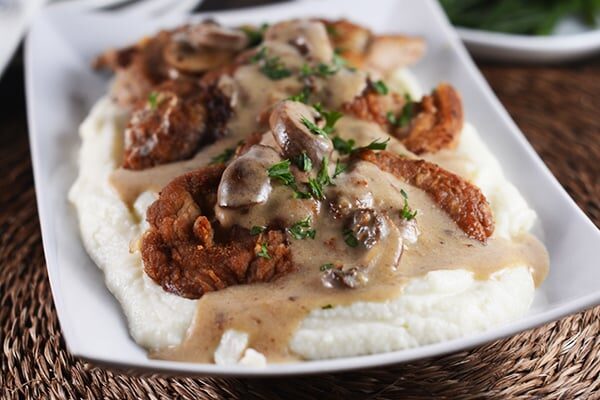 Crispy pork over a bed of mashed potatoes and covered with a brown mushroom sauce. 