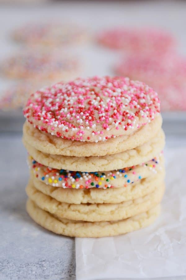 Sugar cookies stacked on top of each other with a few covered in sprinkles. 