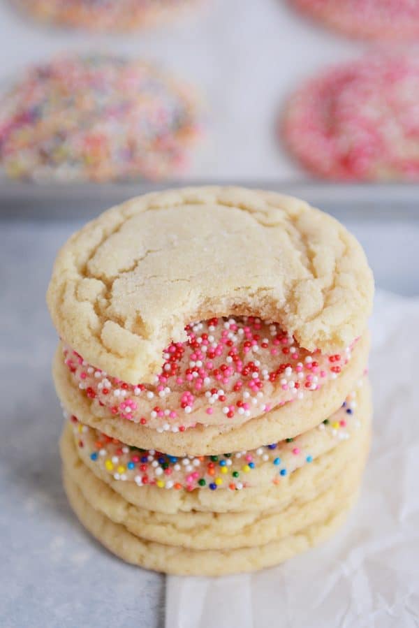 A stack of sugar cookies with the top one with a bite taken out. 