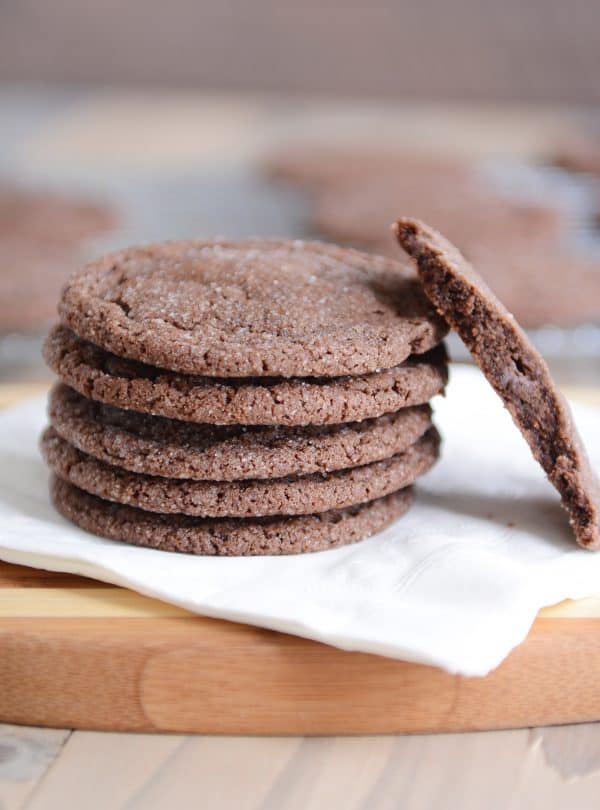 Stack of chocolate sugar cookies on a white napkin with one in half.