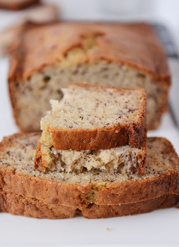 A loaf of banana bread with a few slices cut off and stacked in front of the rest of the loaf. 