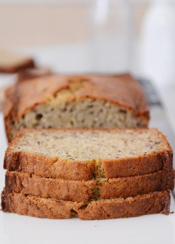 A loaf of banana bread with three slices cut out and stacked in front of the rest of the loaf. 