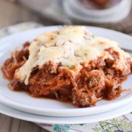 Scoop of Spaghetti squash spaghetti bake topped with cheese on a white plate.