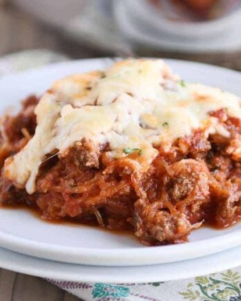 Scoop of Spaghetti squash spaghetti bake topped with cheese on a white plate.