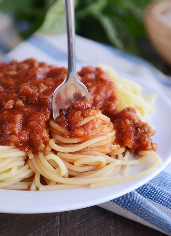 A fork twirling a bite of homemade spaghetti sauce and cooked spaghetti noodles to get ready for a bite. 