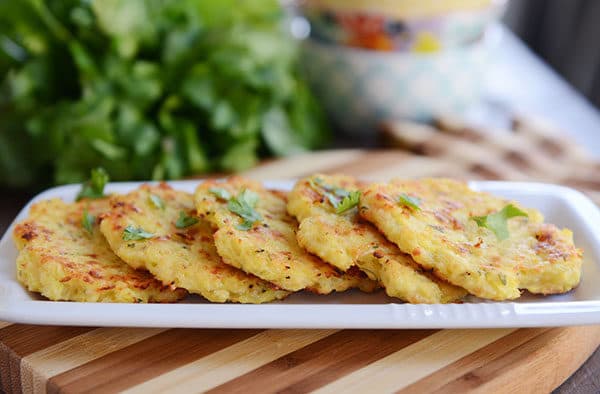 Golden brown spaghetti squash fritters lined up on a white platter.