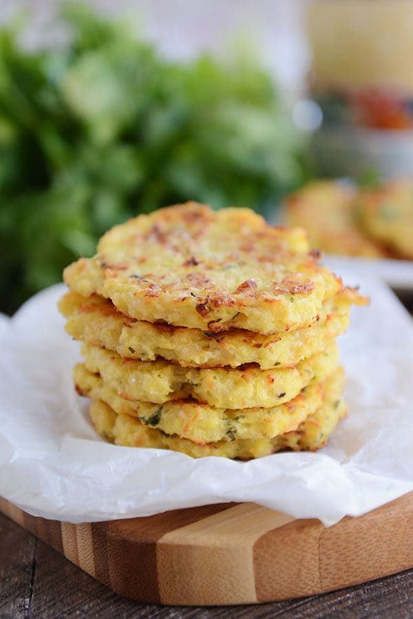 Five golden brown spaghetti squash fritters on a piece of parchment paper.